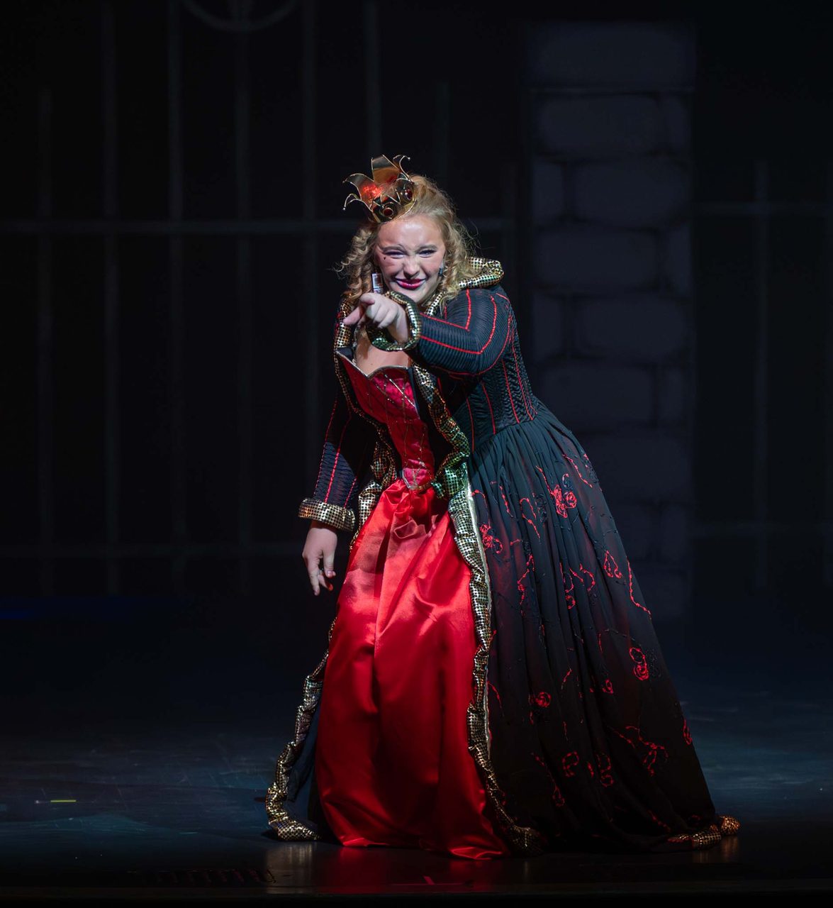 An Aspire performer as the Queen of Hearts in costume on stage