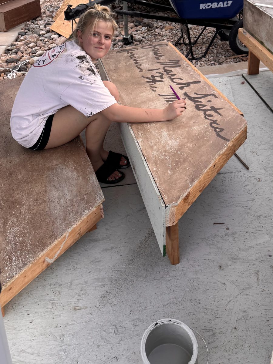 A Young Artist hand-lettering Four March Sisters onto a set piece