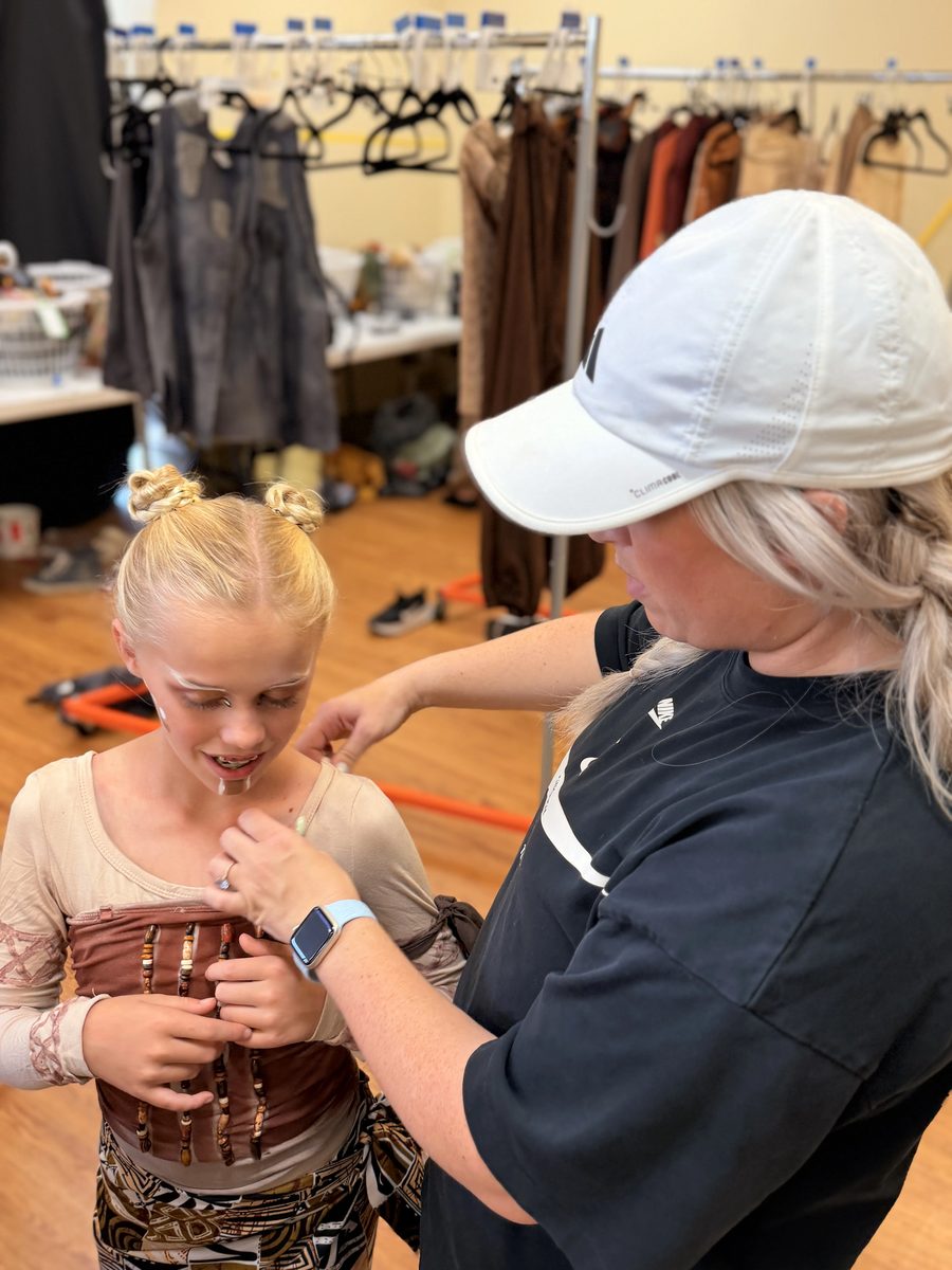 A volunteer fits a beaded costume piece on a Young Artist