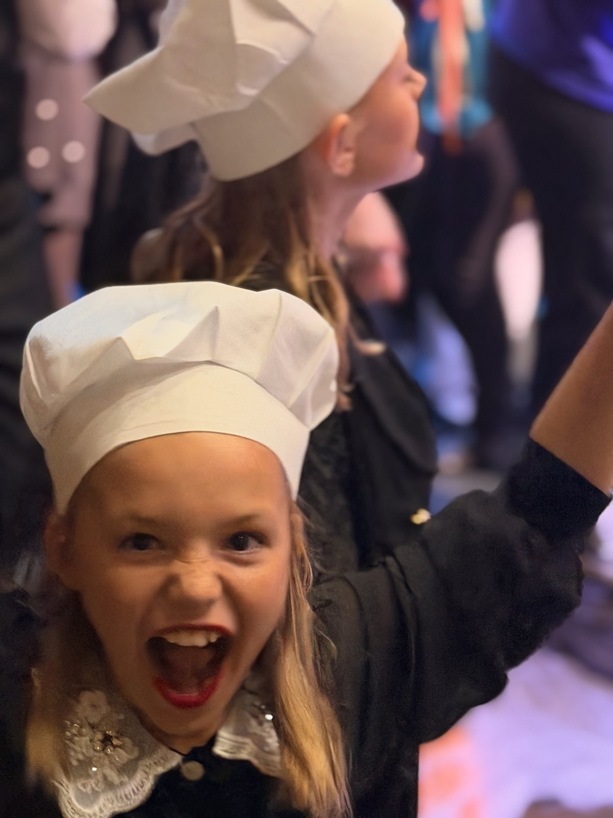 A Villains Night performer in a chef hat cheering with one arm raised