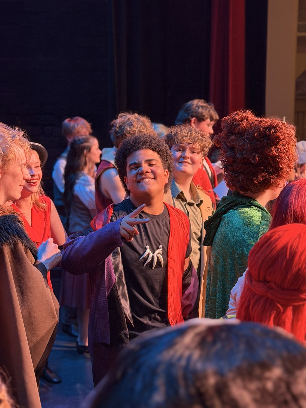 Members of the Villains Night company talking and laughing backstage in costume