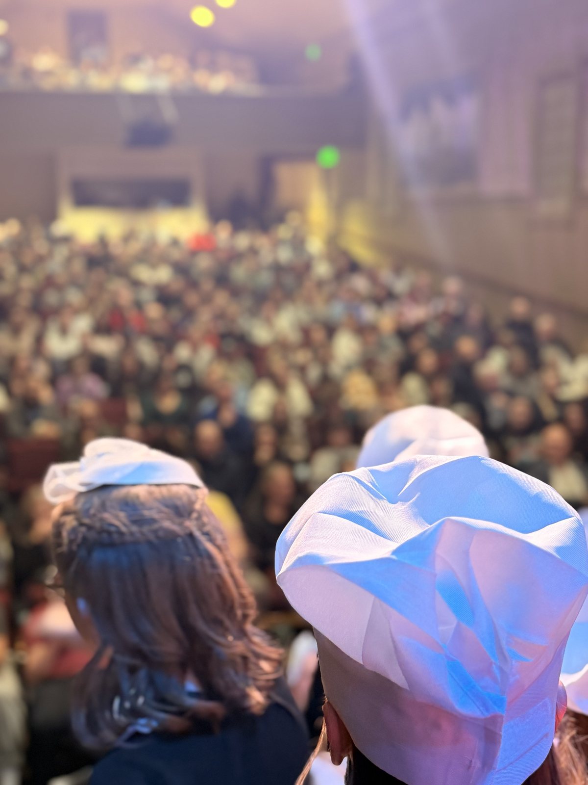 Two Villains Night performers in chef hats looking out from the stage at a full audience