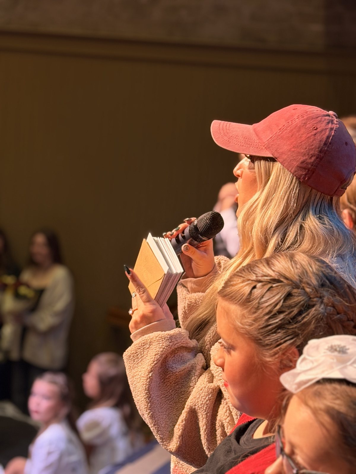 An Encore leader reading thank yous from a notebook into a microphone on stage