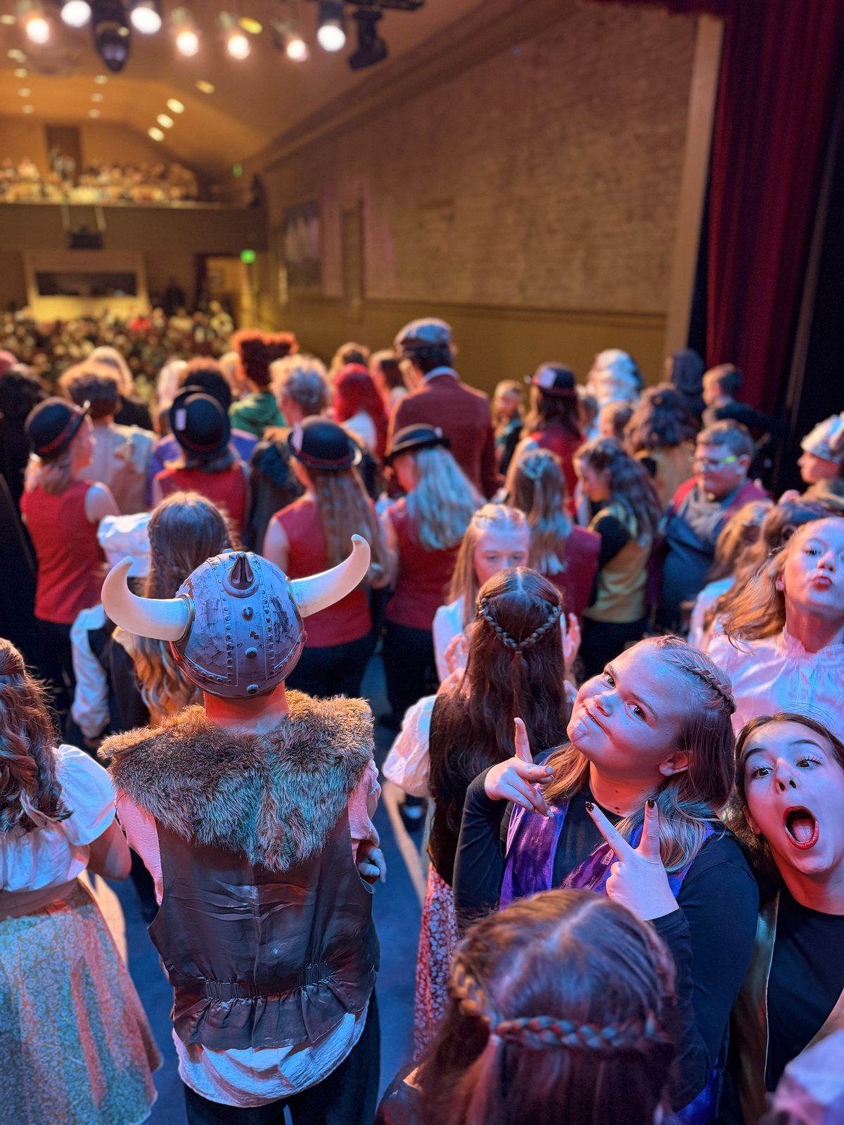 Villains Night performers in costume, one in a horned helmet, gathered on stage