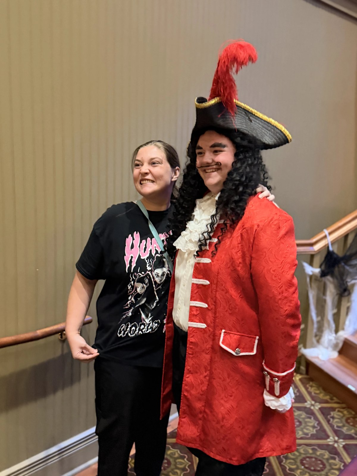 Captain Hook in a red coat and feathered hat posing for a photo with a guest in the lobby