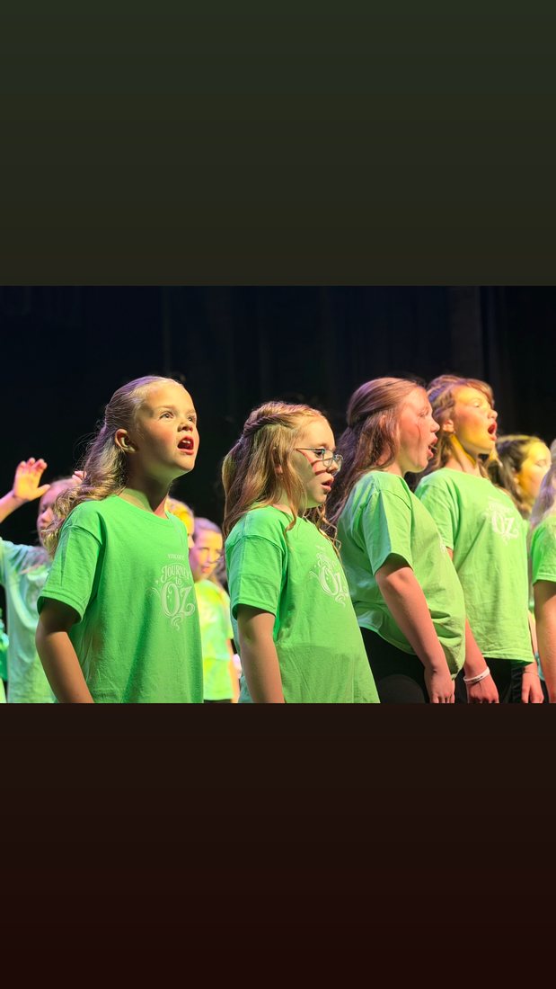 Young Artists in green Journey to Oz camp shirts singing on stage
